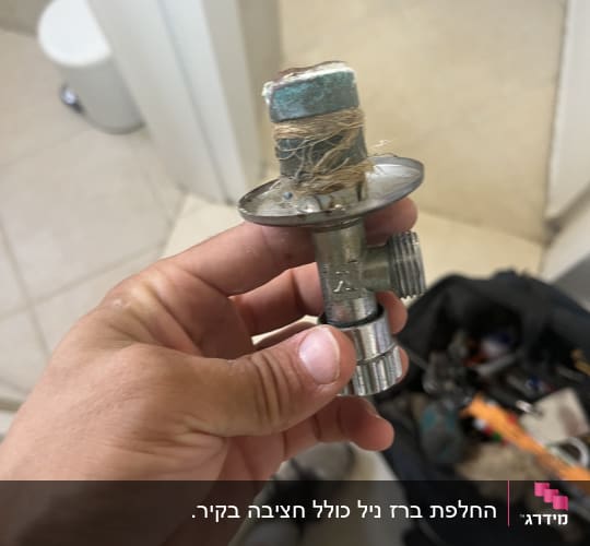 יד מחזיקה חלק אינסטלציה עם חוטים, תיק כלים ברקע